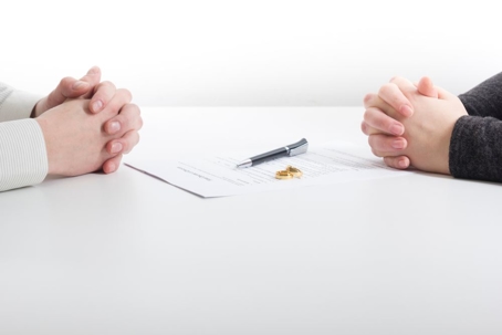 rings on divorce papers with two hands across from each other